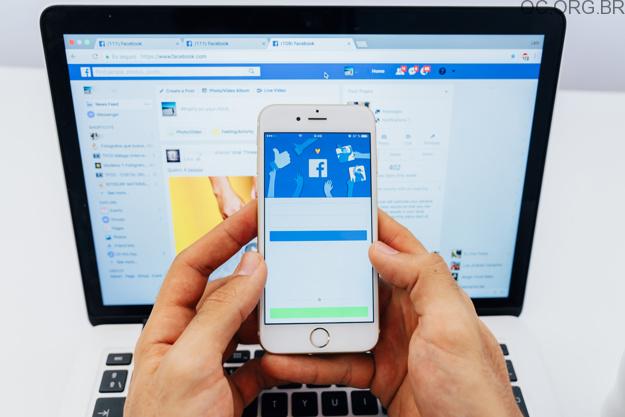 pessoa segurando celular com perfil facebook
